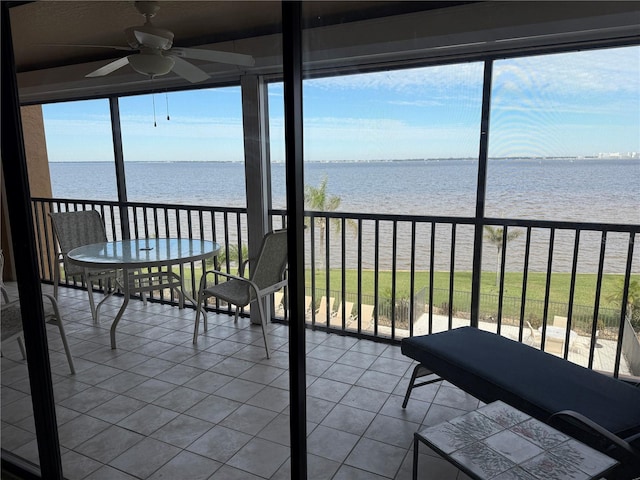 unfurnished sunroom featuring a wealth of natural light, ceiling fan, and a water view