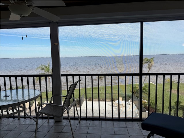 sunroom with a view of the beach, ceiling fan, and a water view