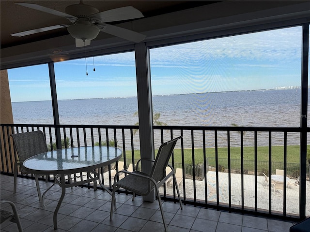 sunroom / solarium with a view of the beach, ceiling fan, and a water view