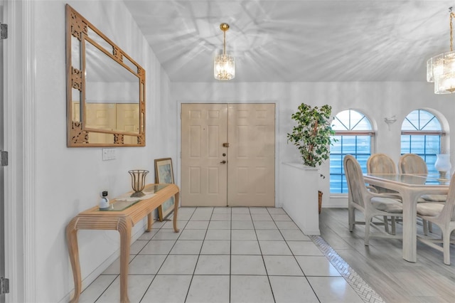 tiled entrance foyer featuring an inviting chandelier