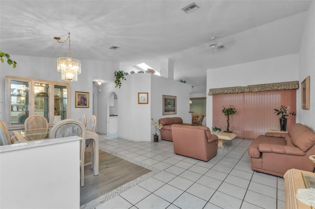 tiled living room with a notable chandelier and vaulted ceiling