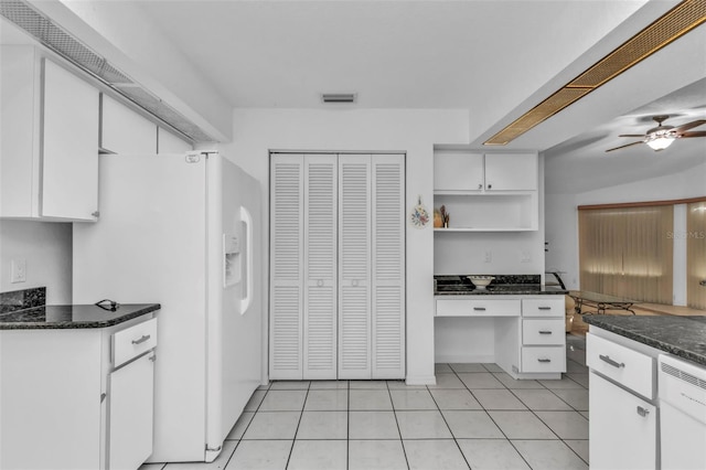 kitchen with white appliances, built in desk, light tile patterned floors, and white cabinets