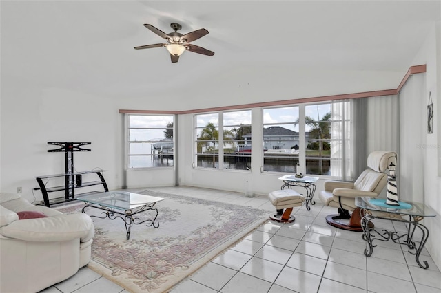 living room with a water view, ceiling fan, vaulted ceiling, and light tile patterned floors