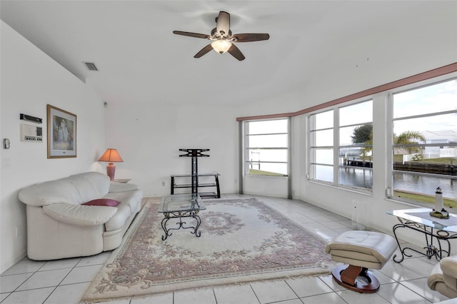 living room featuring light tile patterned floors, vaulted ceiling, ceiling fan, and a water view