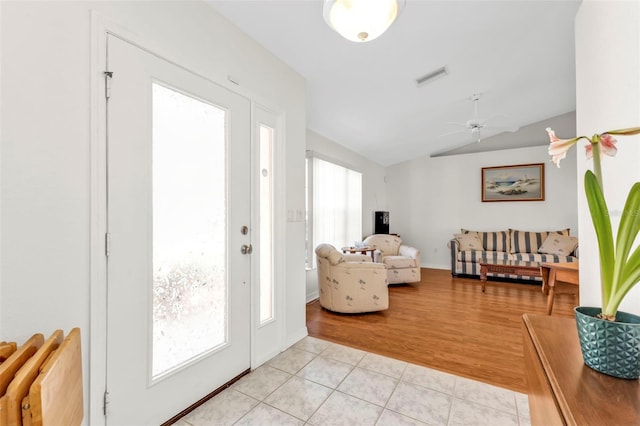 entryway featuring lofted ceiling, light tile patterned floors, and ceiling fan