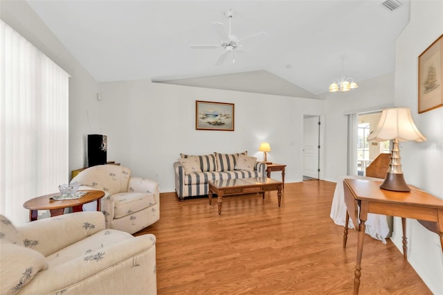 living room with ceiling fan with notable chandelier, vaulted ceiling, and light wood-type flooring