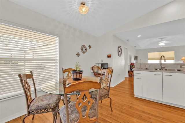 dining area featuring vaulted ceiling, sink, ceiling fan, and light hardwood / wood-style flooring