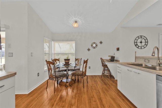 dining room with vaulted ceiling, sink, and light hardwood / wood-style floors