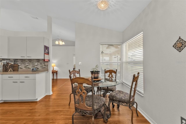 dining space featuring lofted ceiling, an inviting chandelier, and light hardwood / wood-style floors