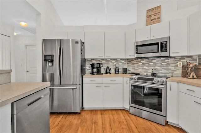 kitchen with stainless steel appliances, white cabinetry, tasteful backsplash, and light wood-type flooring