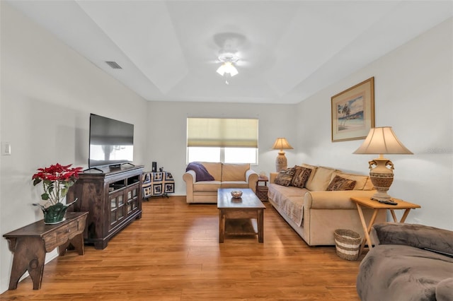 living room featuring a tray ceiling, plenty of natural light, light hardwood / wood-style floors, and ceiling fan