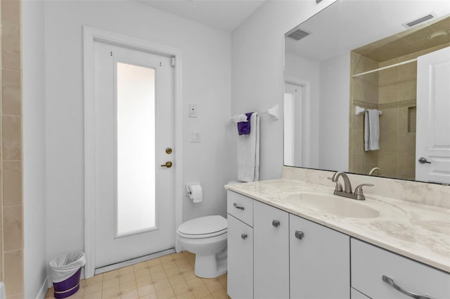 bathroom featuring vanity, toilet, and a tile shower