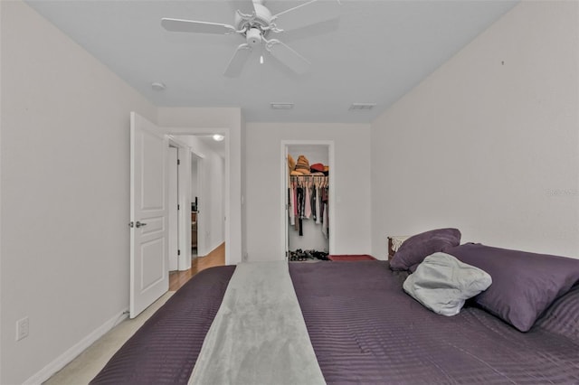 carpeted bedroom with ceiling fan, a spacious closet, and a closet