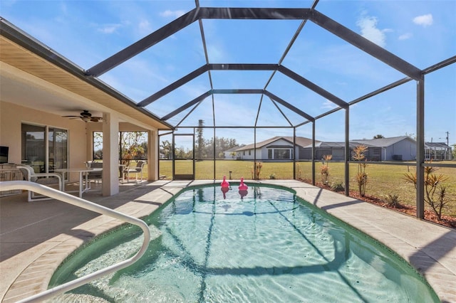 view of swimming pool featuring a yard, a patio, ceiling fan, and glass enclosure