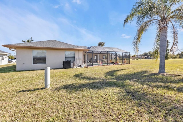 rear view of property featuring a lanai, a lawn, and central AC