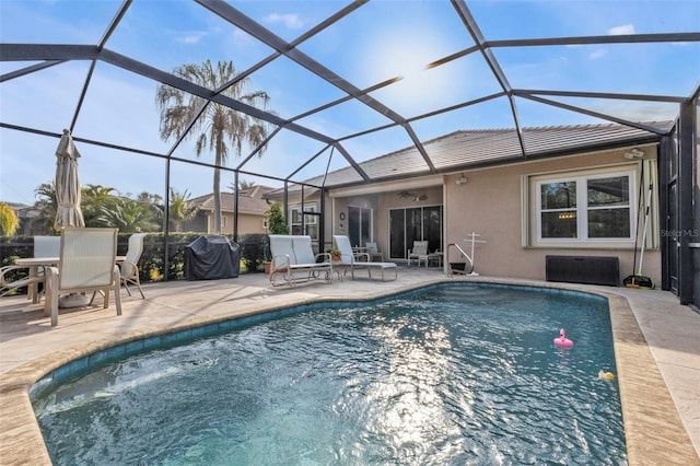 view of pool with a patio, area for grilling, ceiling fan, and glass enclosure