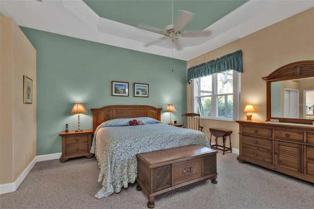 bedroom featuring ceiling fan, a tray ceiling, and light carpet