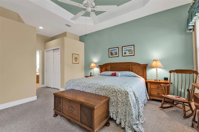 carpeted bedroom with a closet, ceiling fan, and a tray ceiling