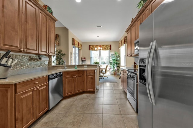 kitchen featuring appliances with stainless steel finishes, tasteful backsplash, sink, hanging light fixtures, and light tile patterned floors