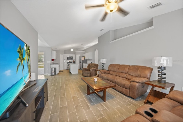 living room with ceiling fan, light hardwood / wood-style floors, and vaulted ceiling