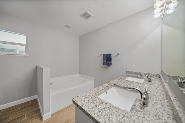 bathroom with vanity, a textured ceiling, and a washtub