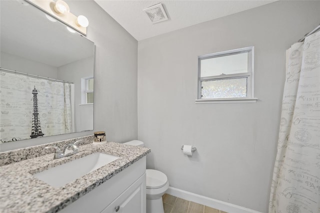 bathroom with vanity, toilet, and a textured ceiling