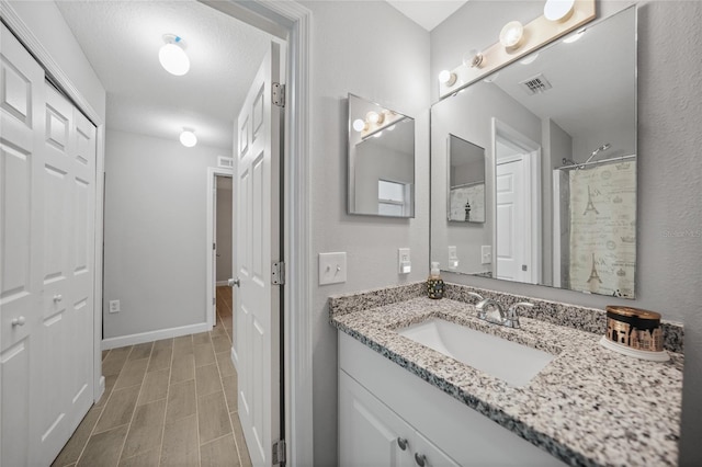 bathroom featuring vanity, a textured ceiling, and a shower