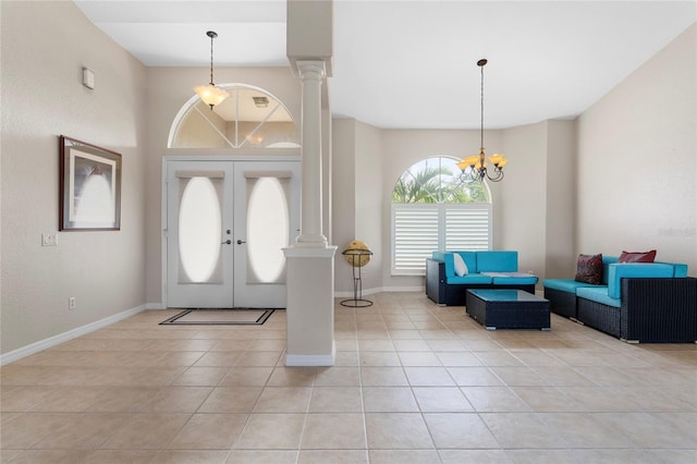 tiled entryway featuring an inviting chandelier, decorative columns, and french doors