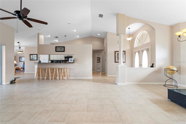 living room featuring light tile patterned floors, ceiling fan, high vaulted ceiling, french doors, and ornate columns