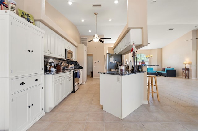 kitchen with light tile patterned flooring, a breakfast bar, vaulted ceiling, appliances with stainless steel finishes, and white cabinets