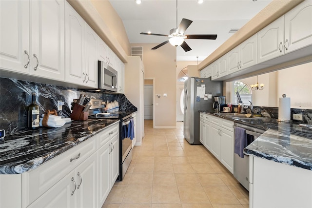 kitchen with dark stone countertops, white cabinetry, stainless steel appliances, and light tile patterned flooring