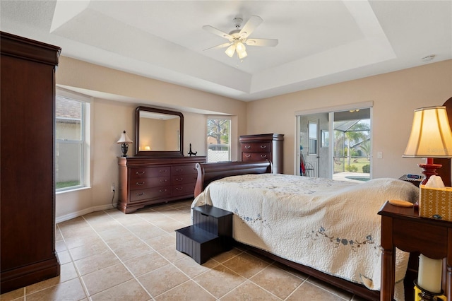 bedroom with multiple windows, access to exterior, ceiling fan, and a tray ceiling