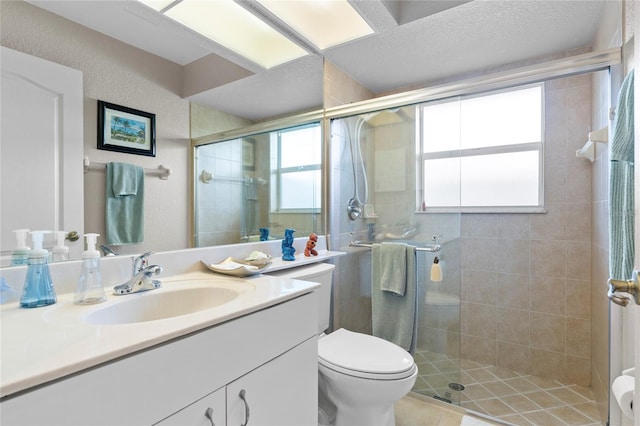 bathroom featuring vanity, a textured ceiling, a shower with shower door, tile patterned floors, and toilet