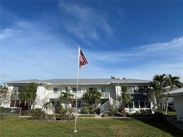 view of front facade with metal roof, stairway, and a front yard