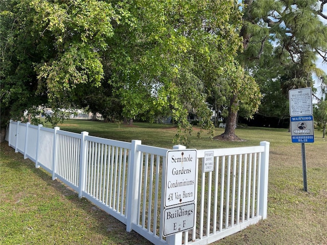 view of gate with fence and a lawn