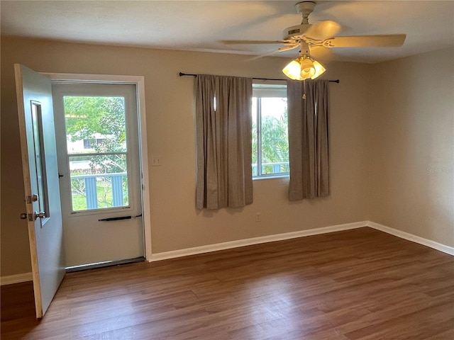 empty room featuring dark wood finished floors, plenty of natural light, and baseboards