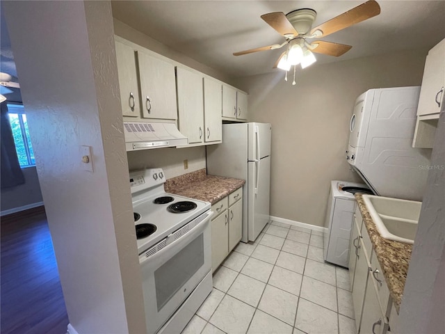 kitchen featuring white appliances, light tile patterned floors, stacked washer / drying machine, white cabinetry, and exhaust hood