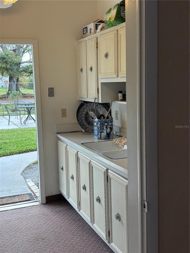 interior space featuring decorative backsplash, light countertops, a sink, and dark colored carpet