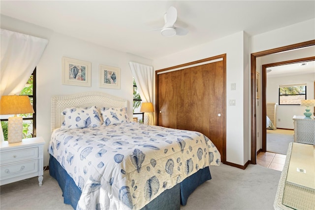 bedroom featuring light colored carpet, ceiling fan, and a closet