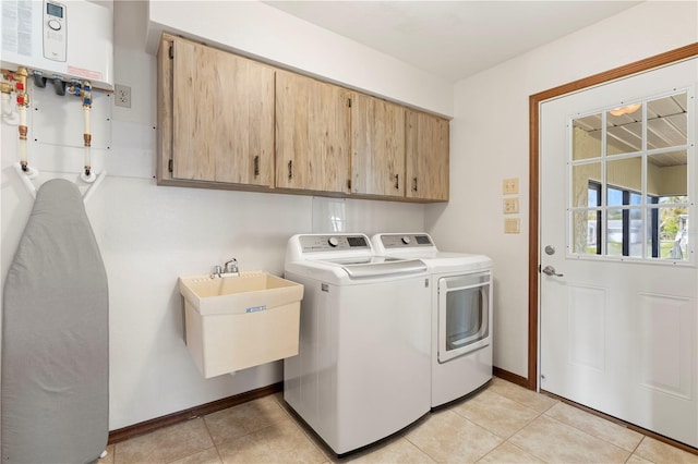 laundry room with water heater, sink, cabinets, light tile patterned floors, and washing machine and dryer