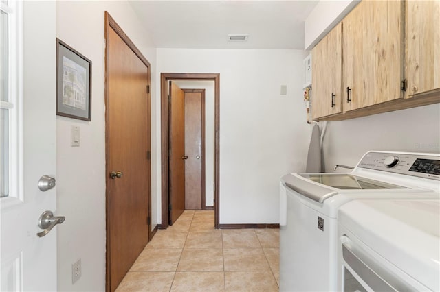 clothes washing area with cabinets, washing machine and dryer, and light tile patterned floors