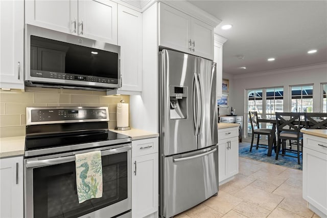 kitchen with white cabinetry, backsplash, ornamental molding, and stainless steel appliances