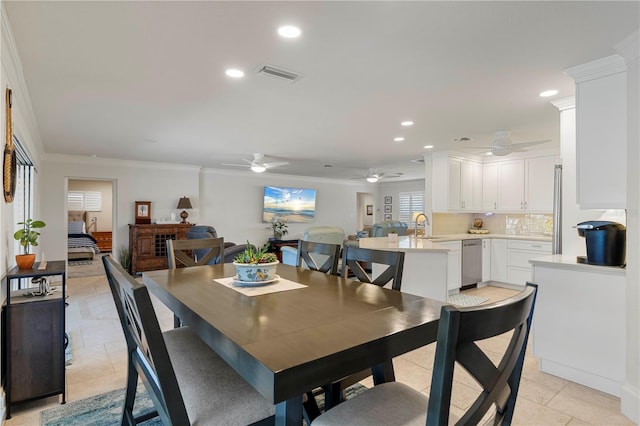 tiled dining area featuring sink, crown molding, and ceiling fan