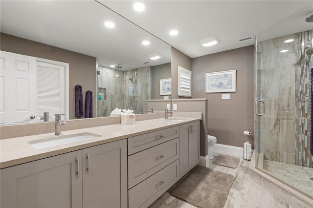 bathroom featuring a shower with door, vanity, and toilet