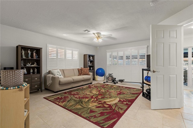 tiled living room with ceiling fan, a wealth of natural light, and a textured ceiling