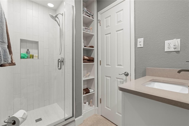 bathroom with built in shelves, vanity, tile patterned flooring, and a shower with door