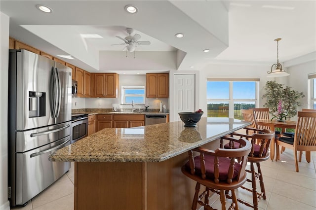 kitchen with hanging light fixtures, light tile patterned floors, a kitchen island, and appliances with stainless steel finishes