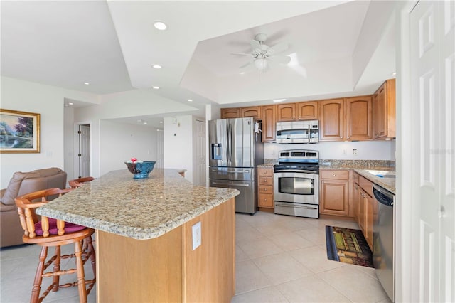 kitchen featuring stainless steel appliances, a center island, a breakfast bar, and a tray ceiling