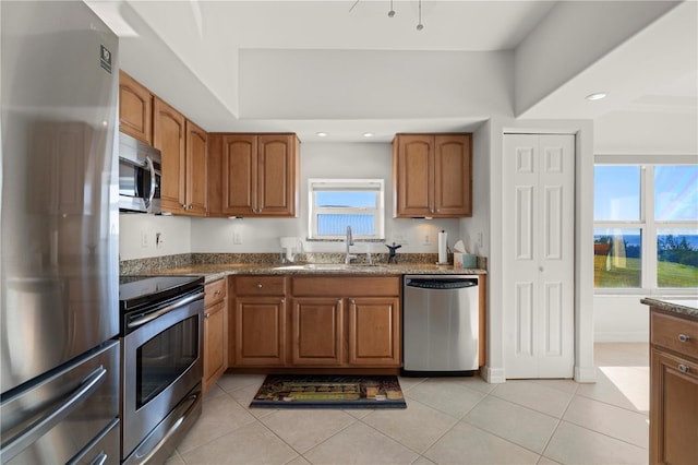 kitchen with light tile patterned flooring, stainless steel appliances, sink, and dark stone countertops