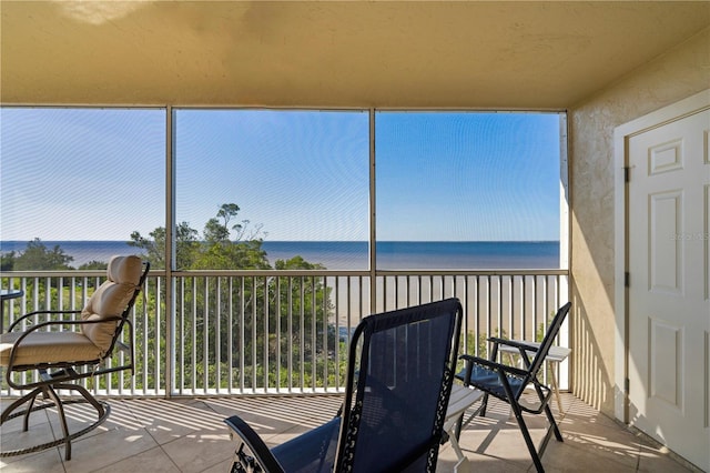 sunroom with a water view and a view of the beach